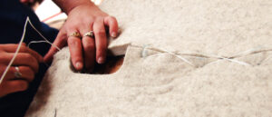 A woman handstitching a saddle pad.